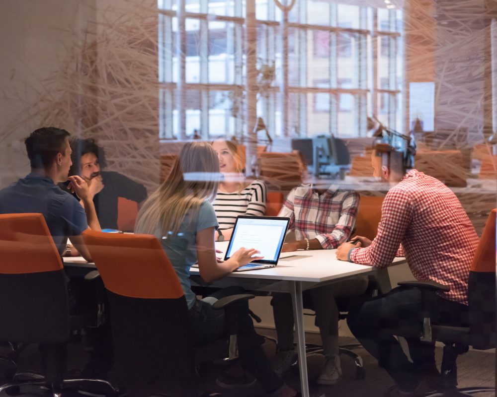 Multiethnic startup business team on meeting in modern bright office interior brainstorming, working on laptop and tablet computer